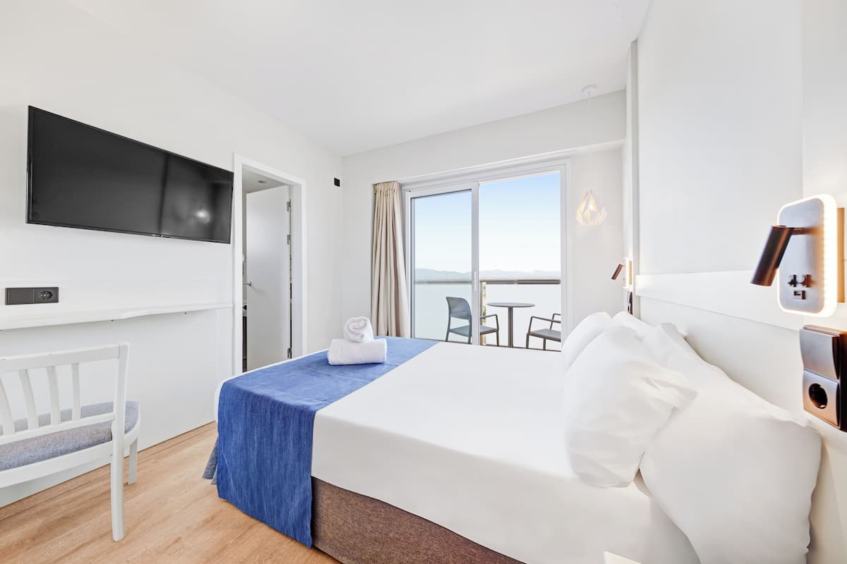 Ein Hotelzimmer mit Bett, Wand-Fernseher, Schreibtisch und Stuhl.
