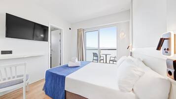 Habitación de hotel con cama, televisión montada en la pared, escritorio y una silla.
