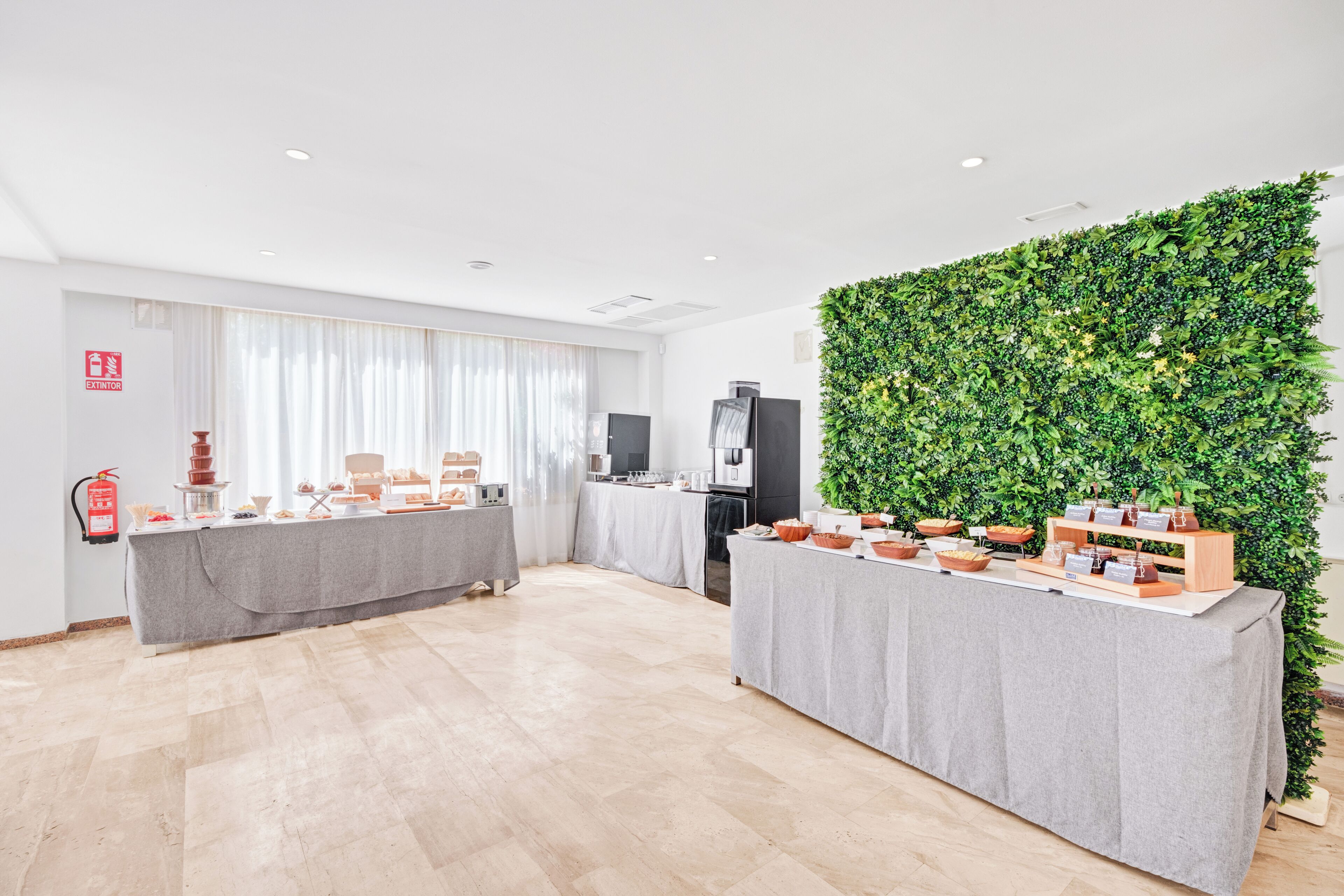 A modern conference room with a long table, a green wall, and a fire extinguisher on the wall.