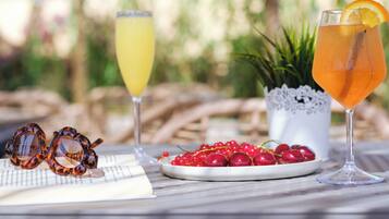 A table with two drinks, a pair of sunglasses, and a plate of red berries.