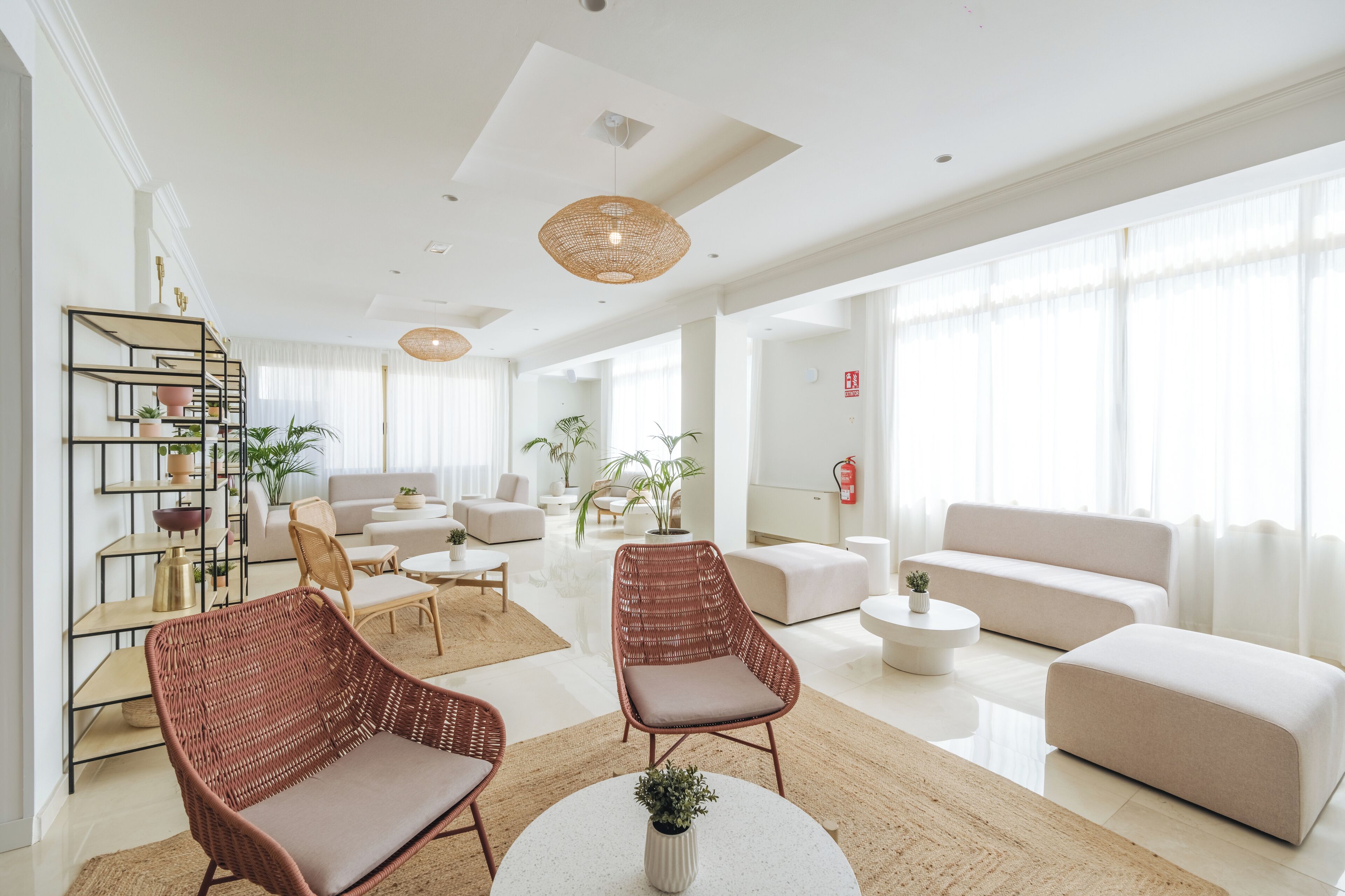 Un salon moderne comprenant un ensemble de canapés, deux fauteuils en osier, une table basse et une bibliothèque.