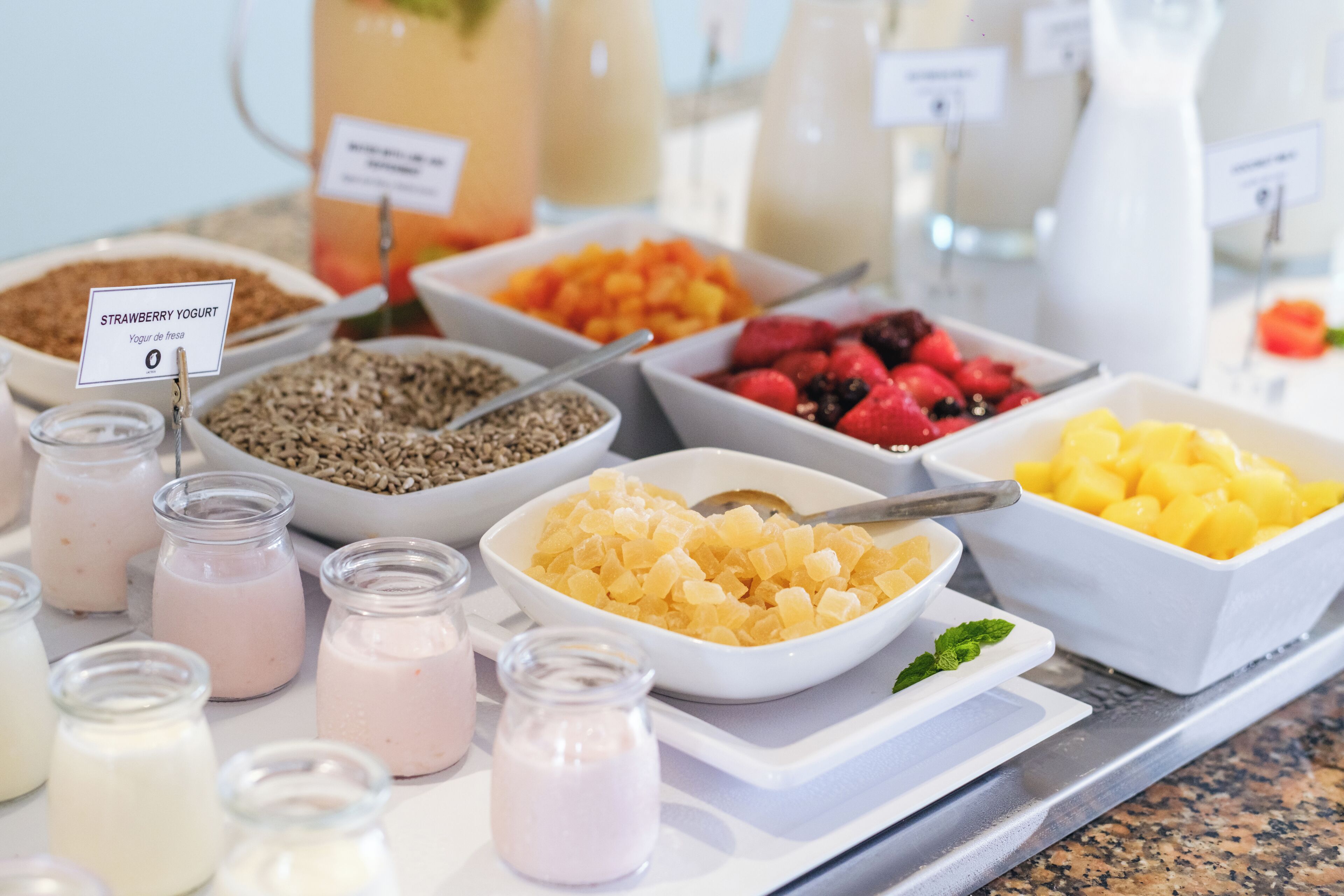 Un bufé con diversas opciones de comida, como yogur, frutas y granola.
