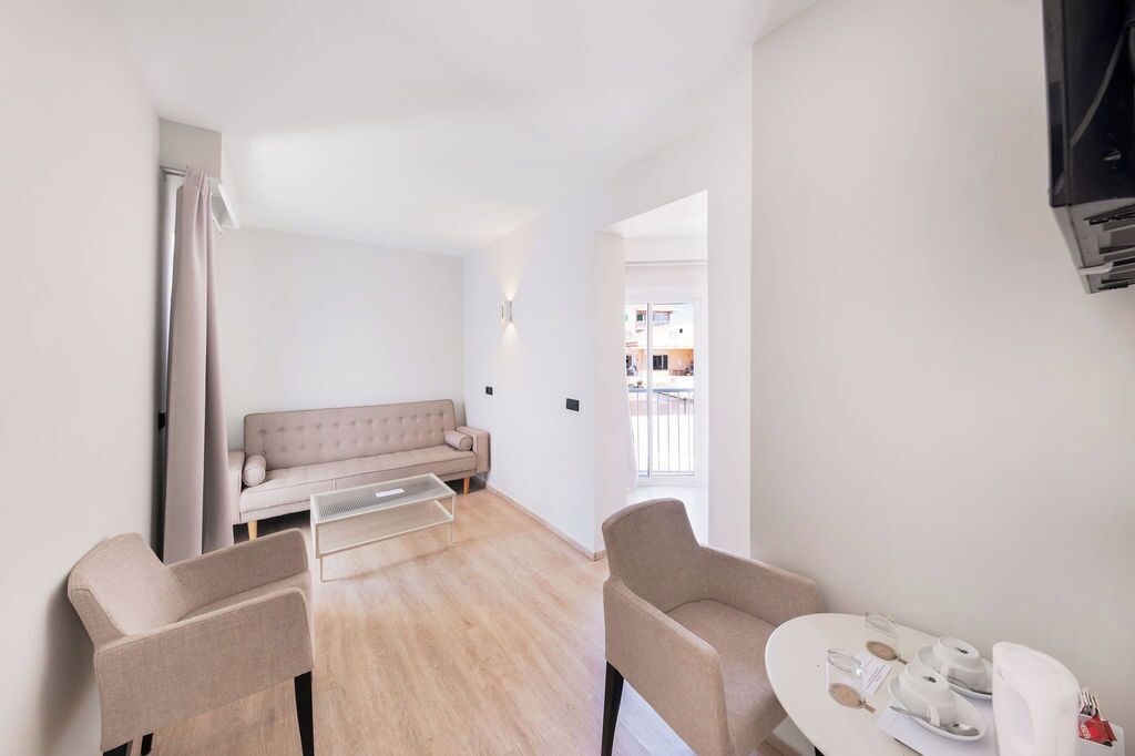 En moderne, minimalistisk stue med en sofa, to lænestole, et sofabord og et spisebord dækket til to personer.