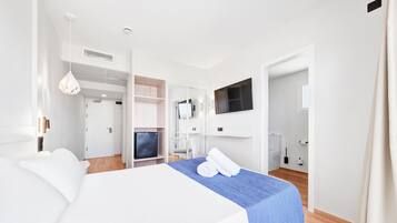 A hotel room with a large bed, a TV, a desk, and a wardrobe.