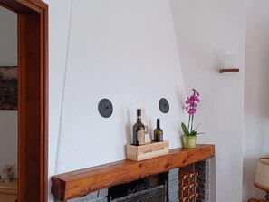 A room with a fireplace, a wooden box labeled "Lambretta," and two bottles on the mantel.