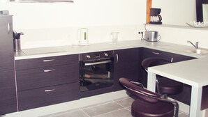 A modern kitchen with dark cabinets, a stainless steel range hood, a coffee maker, and a sink. - House with heated swimming pool 3 km from the beach (PLEUMEUR BODOU)