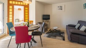 Ein modernes Wohnzimmer mit Essbereich, einer Couch und einem Fernseher.