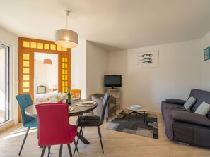 Un salon moderne comprenant un coin repas, un canapé et un téléviseur.