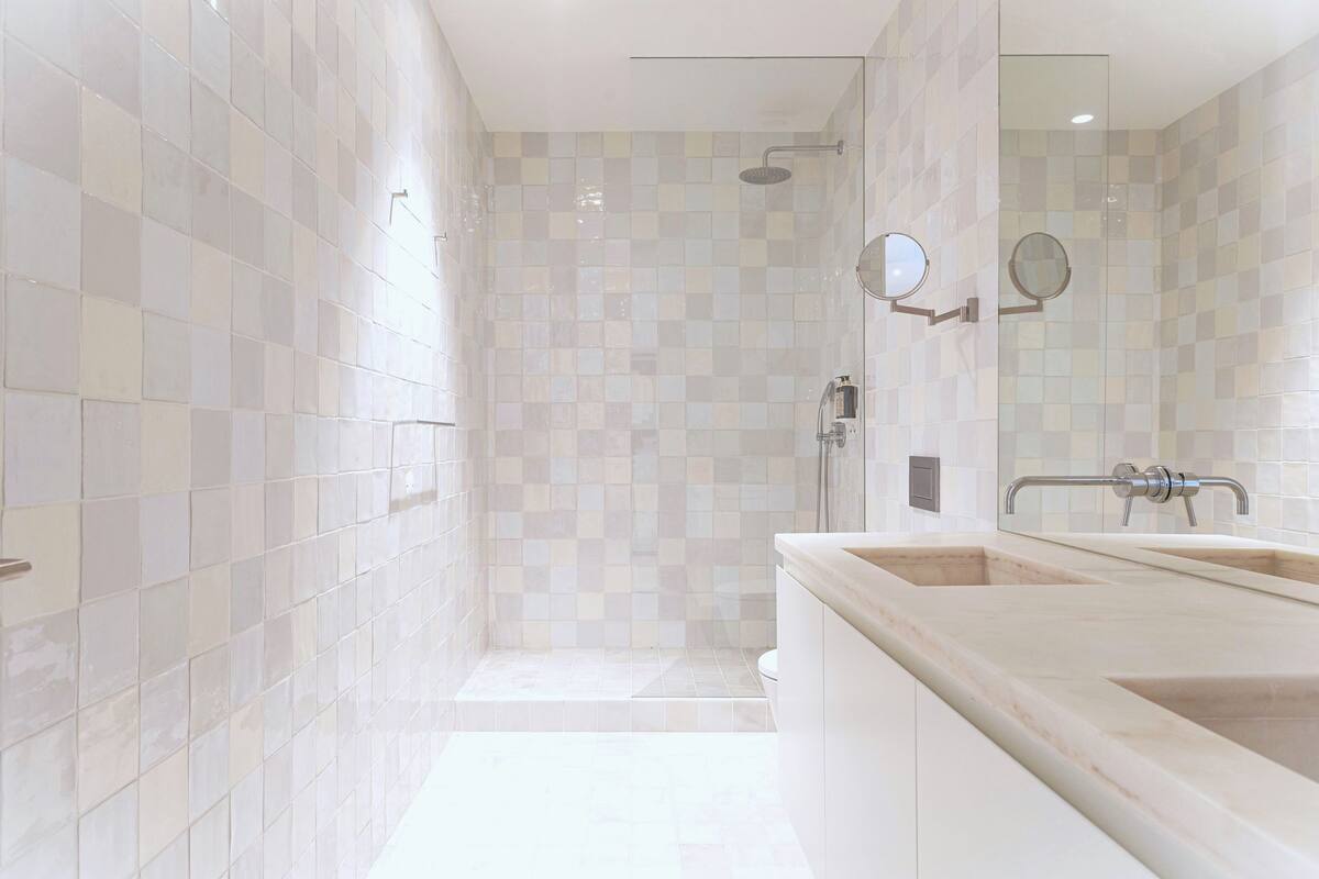A modern bathroom with a walk-in shower, a double sink vanity, and a large mirror.