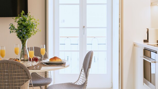 Et morgenbord med en vase blomster, to glas appelsinjuice, en croissant og et fad med frugt.