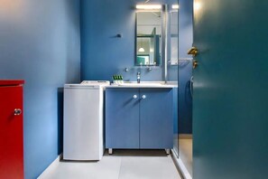 A compact bathroom with a blue wall, a white sink, and a mirror above it.