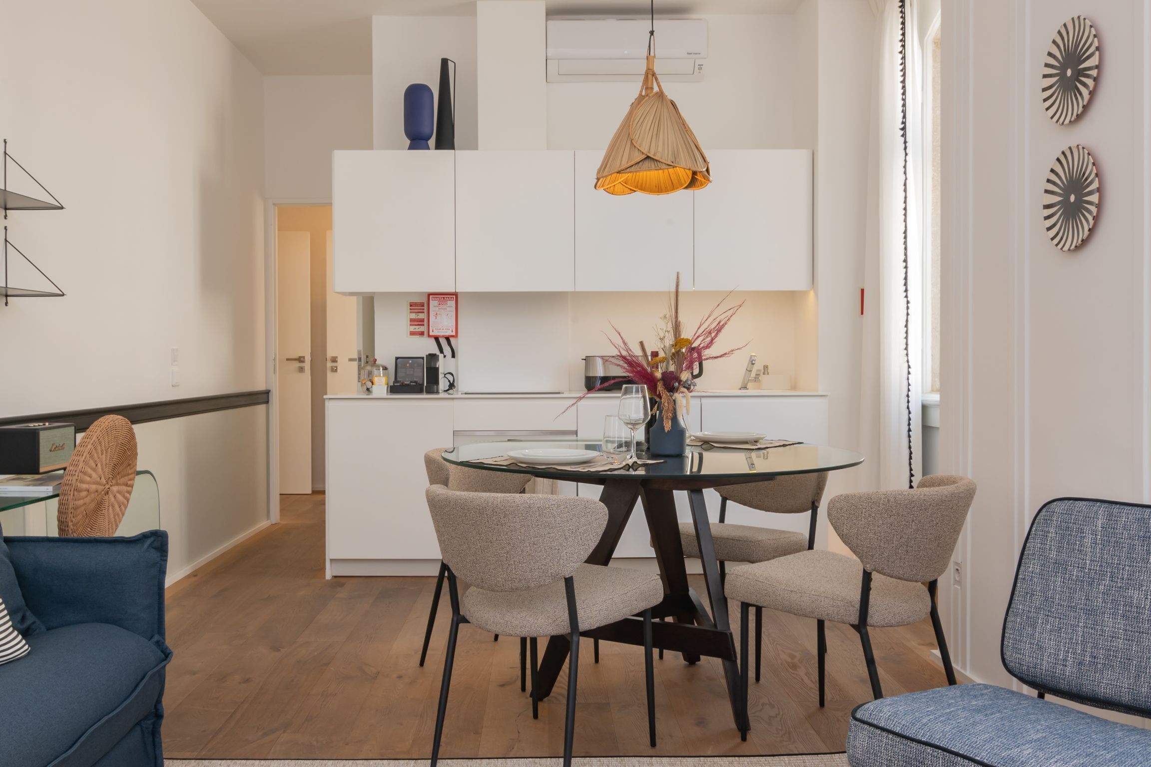 A modern kitchen with white cabinets, a dining table with chairs, and a hanging pendant light.