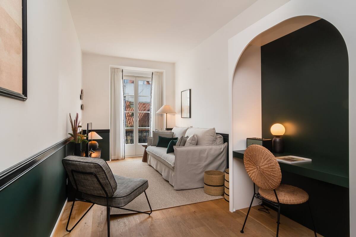 Una sala de estar moderna con un sofá, un sillón, una lámpara y una estantería.