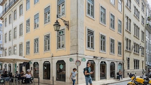 A corner building with multiple Starbucks stores, outdoor seating, and a cobblestone street.