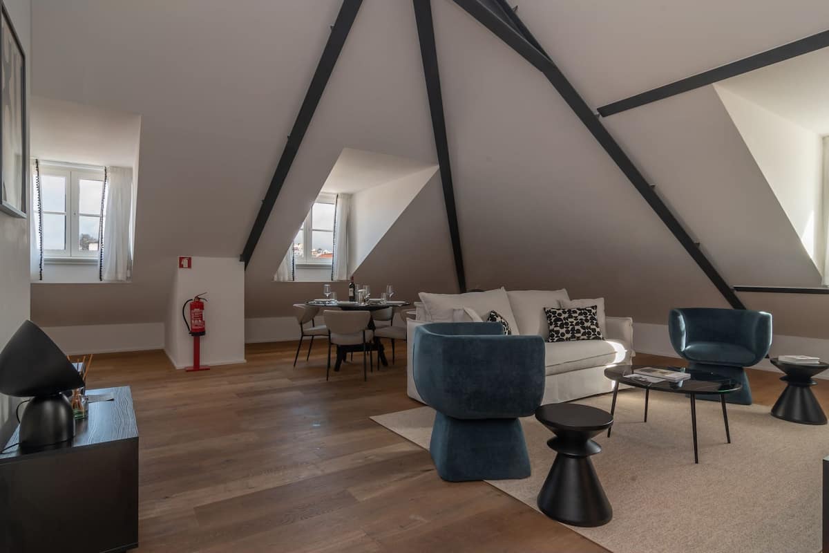 Un loft moderno con vigas a la vista, un comedor y una sala de estar con sofá y sillones.