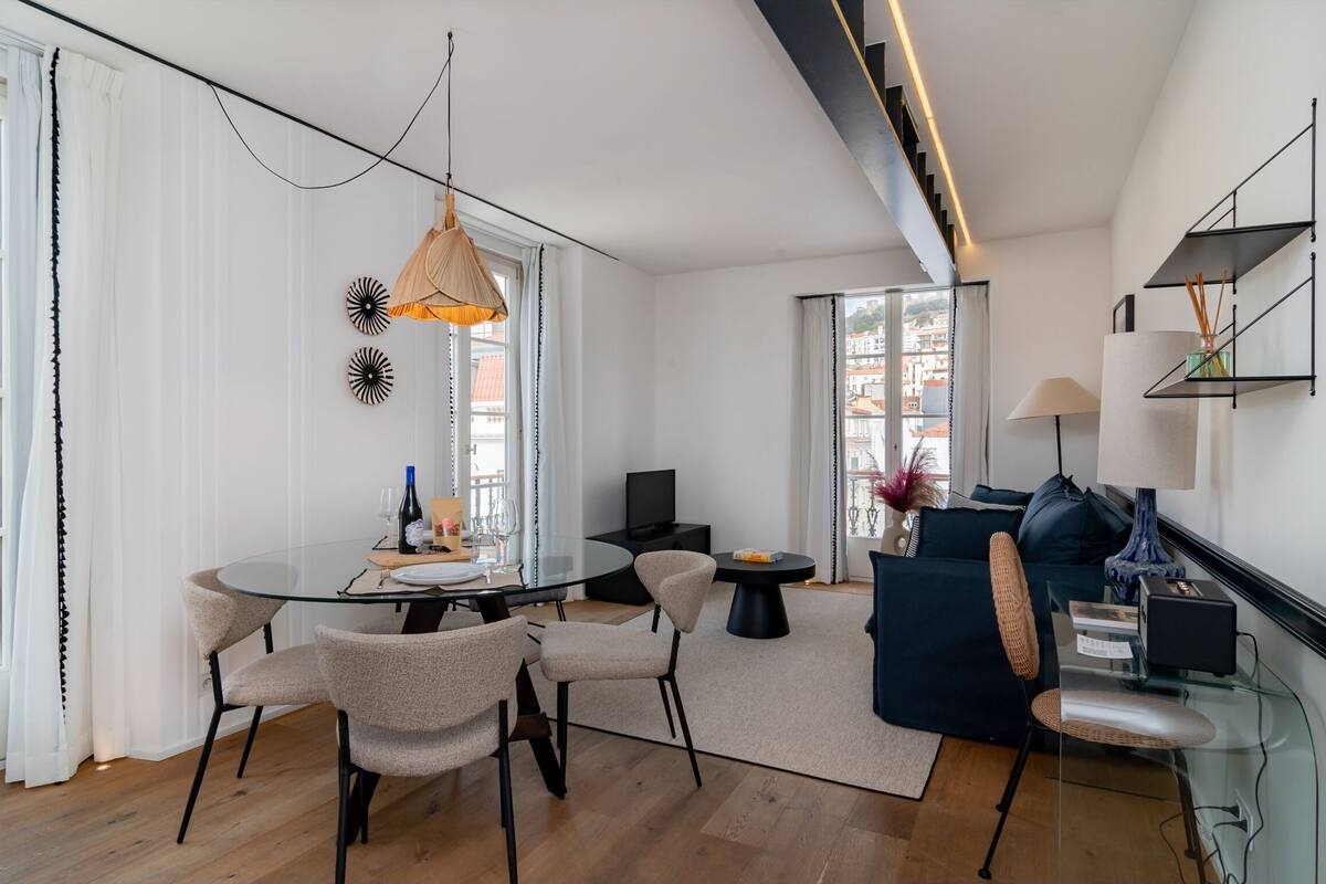 Una sala de estar moderna con una mesa de comedor de vidrio, asientos cómodos, un sofá y un televisor.