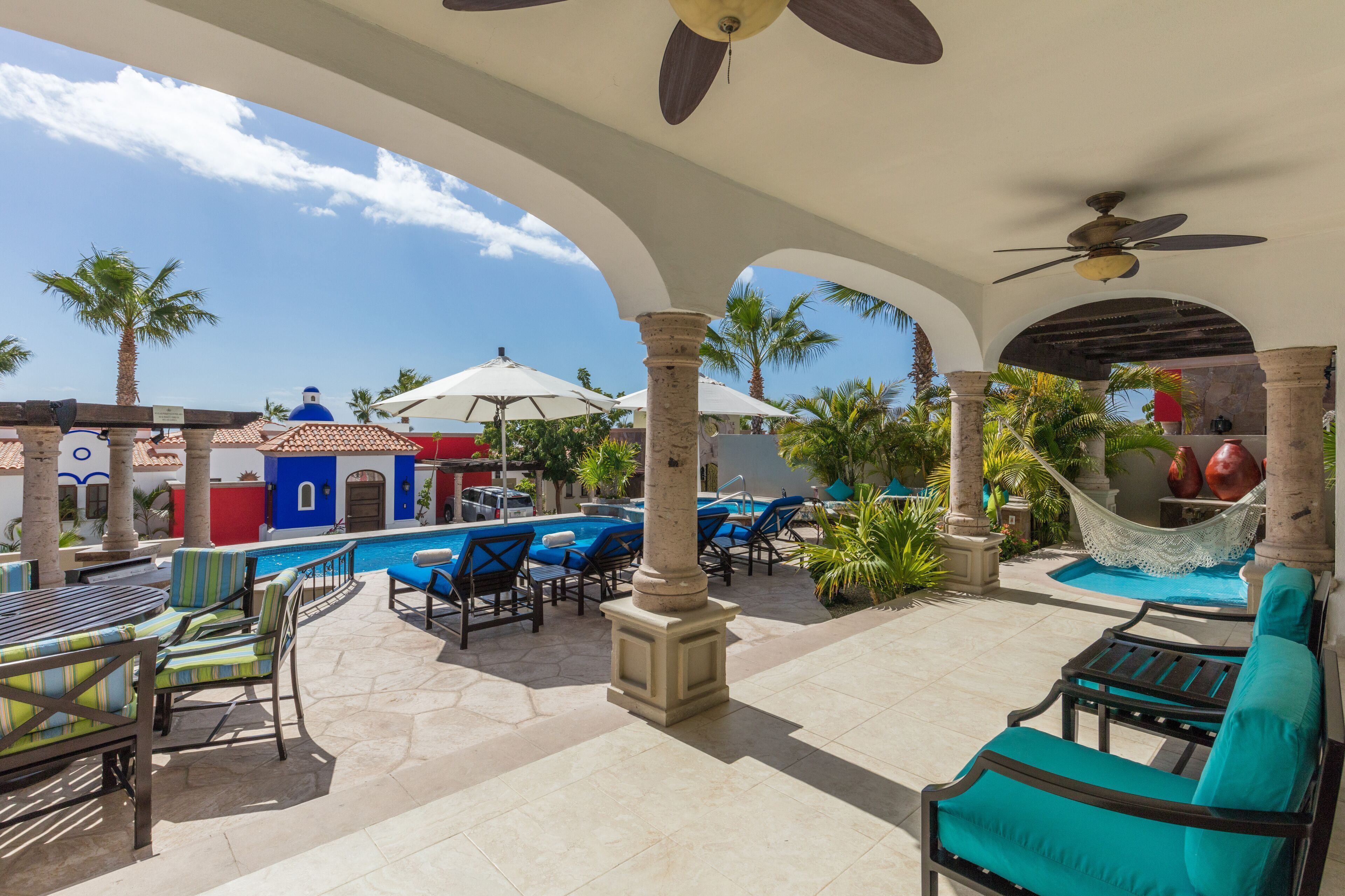 A poolside area with lounge chairs, a hammock, and a pool.