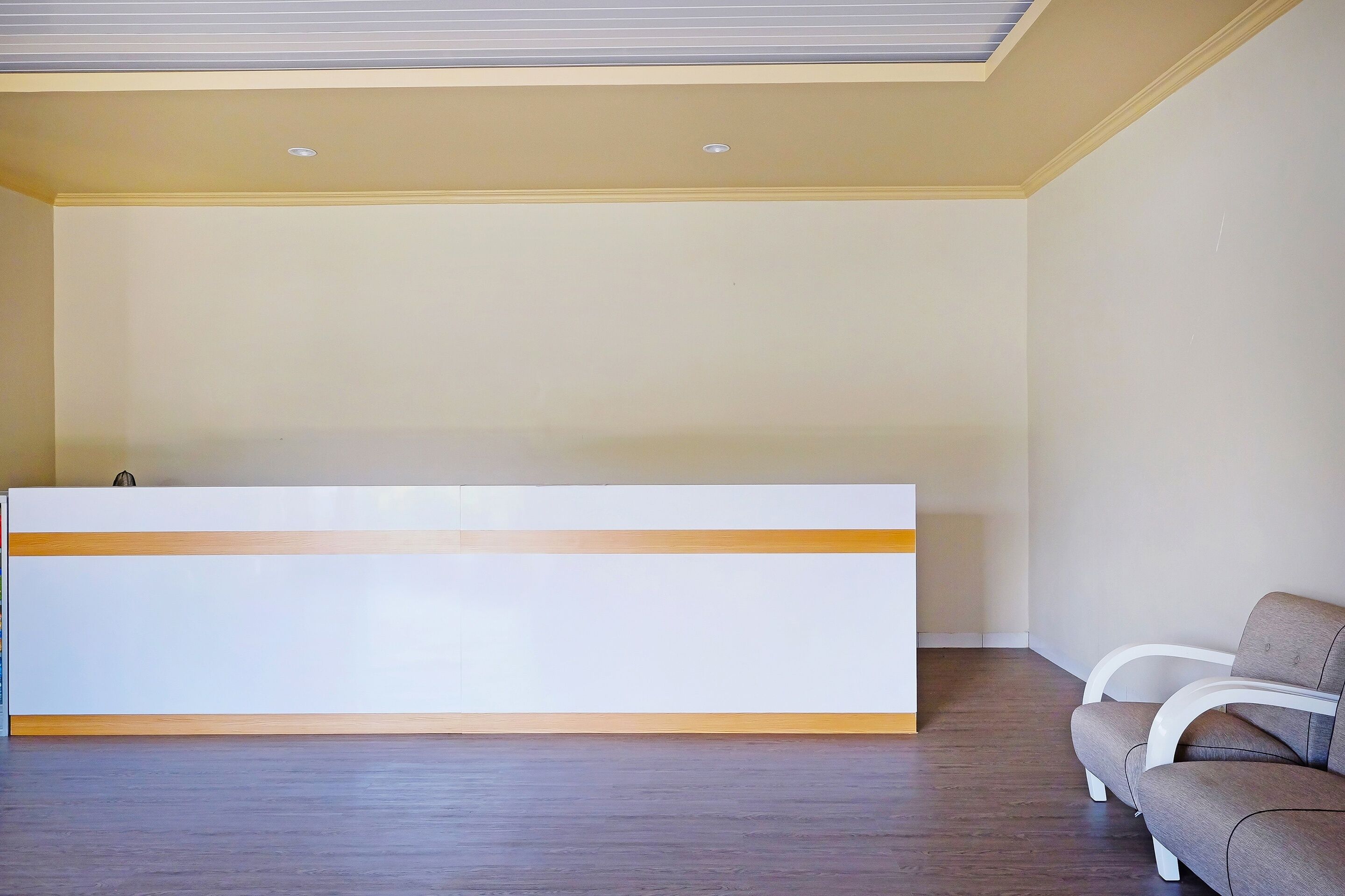 A reception area with a reception desk, a sofa, and a ceiling with recessed lighting.