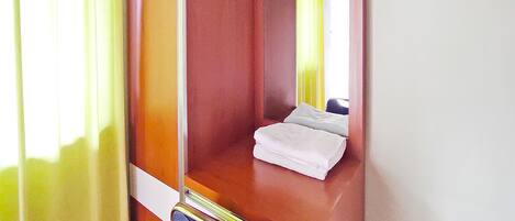 Una habitación de hotel con una cama de madera, un espejo y una ventana con cortinas amarillas.