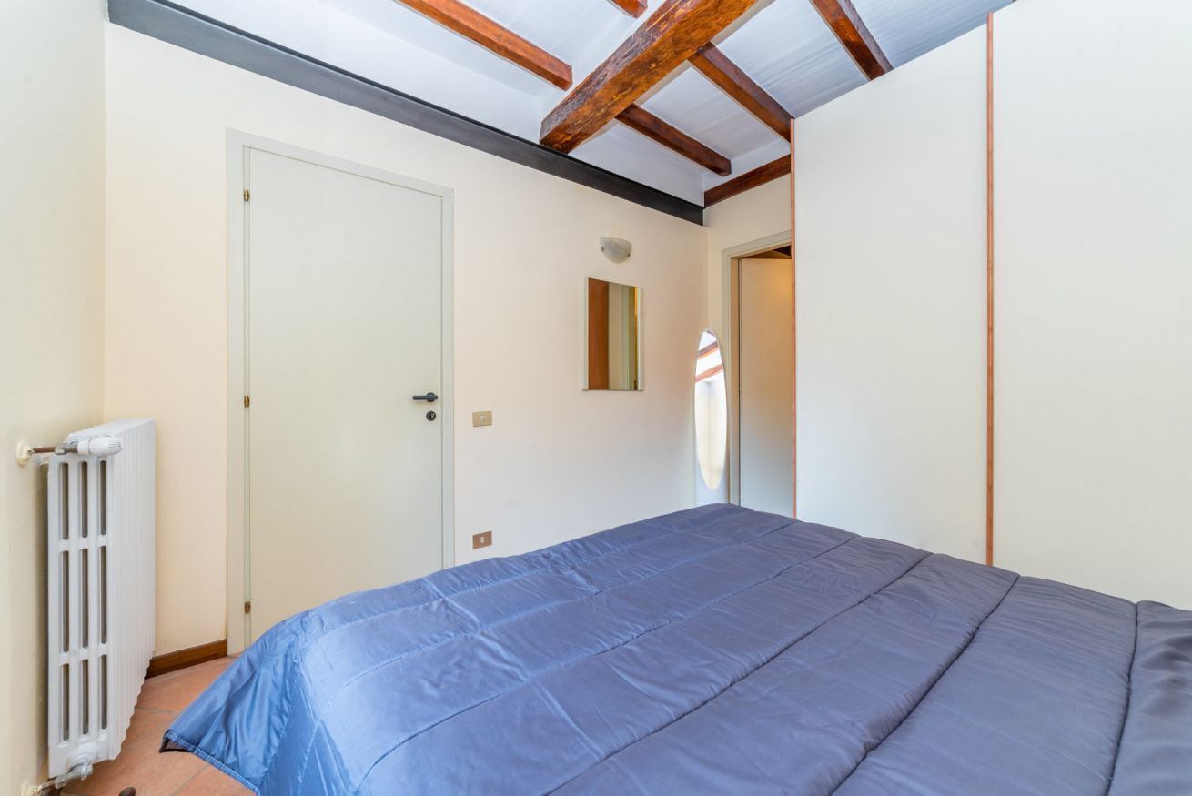 Une chambre à coucher avec un lit, une porte, un radiateur et un petit miroir accroché au mur.