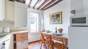 A compact kitchen with wooden chairs, a dining table, and a window. - GuestHost - Two-room apartment located on the second floor of a building, without lift, located in the heart of the historic center of Parma. The property enjoys a central location (ZTL), in a picturesque, popular and lively district, near the Don Gnocch (Parma)