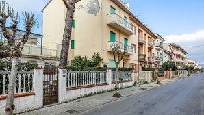 Una calle residencial con edificios de varios pisos, una entrada con reja y una acera.