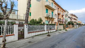Una calle residencial con edificios de varios pisos, una entrada con reja y una acera.