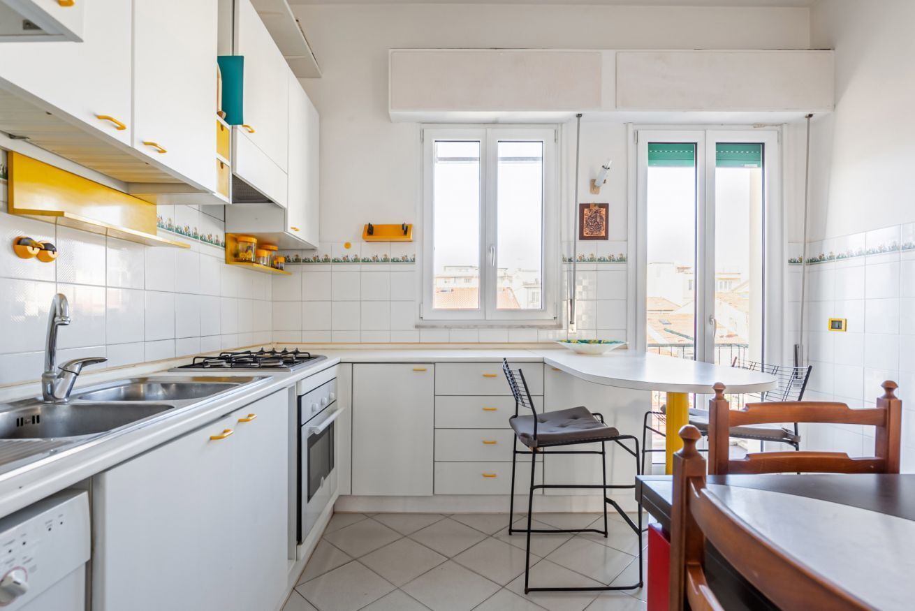 A kitchen with white cabinets, a stove, a sink, and a window.