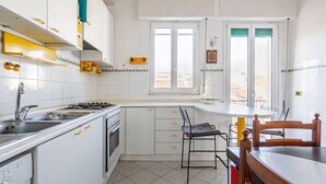 Una cocina con armarios blancos, estufa, lavabo y ventana.