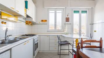 A kitchen with white cabinets, a stove, a sink, and a window.