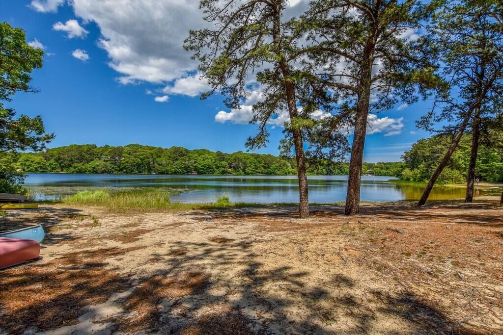 A campsite with a lake, trees, and a clear sky.