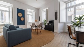 Een moderne woonkamer met een bank, stoelen, een salontafel en een televisie.