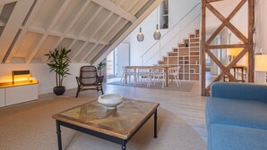 Een ruime loft met een hoge plafond, een eethoek en een trap naar een hoger niveau.