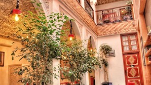 A traditional interior with a dining area, potted plants, and a decorative door. - Saffron Room, Riad Arabic House & Spa (Marrakesh)