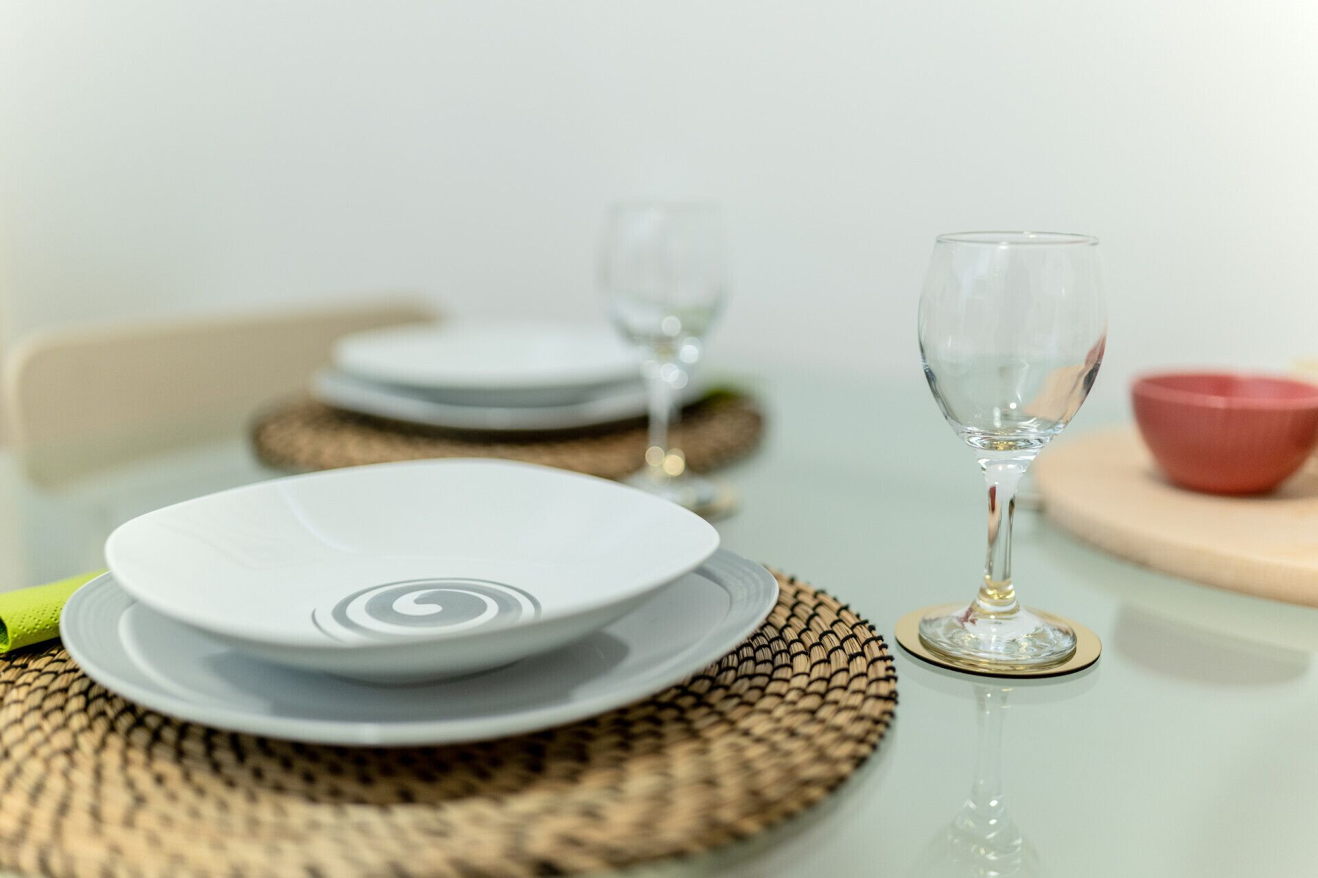 A table set with plates, a wine glass, and a red bowl.