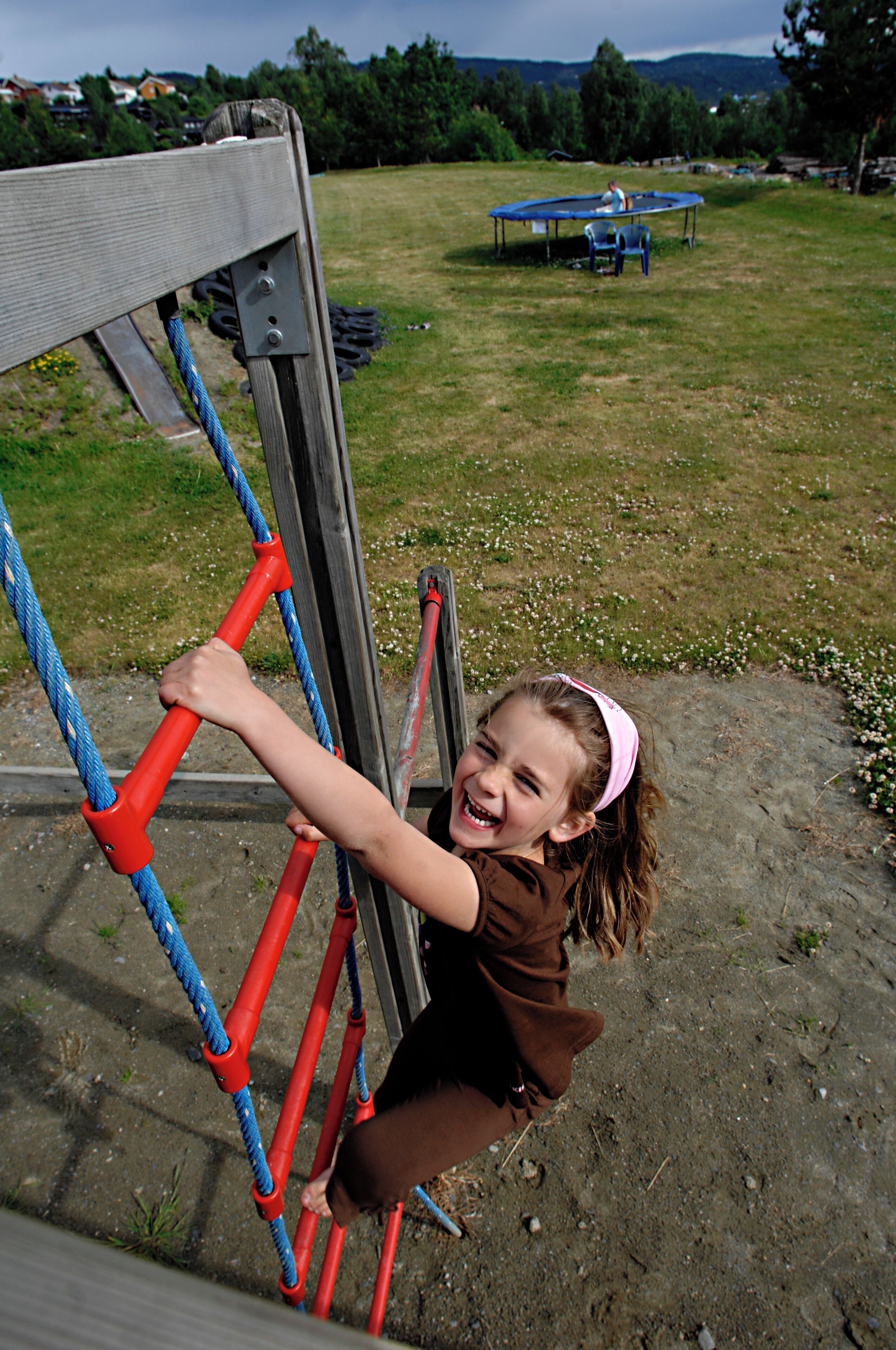 A child climbing a rope ladder structure outdoors.