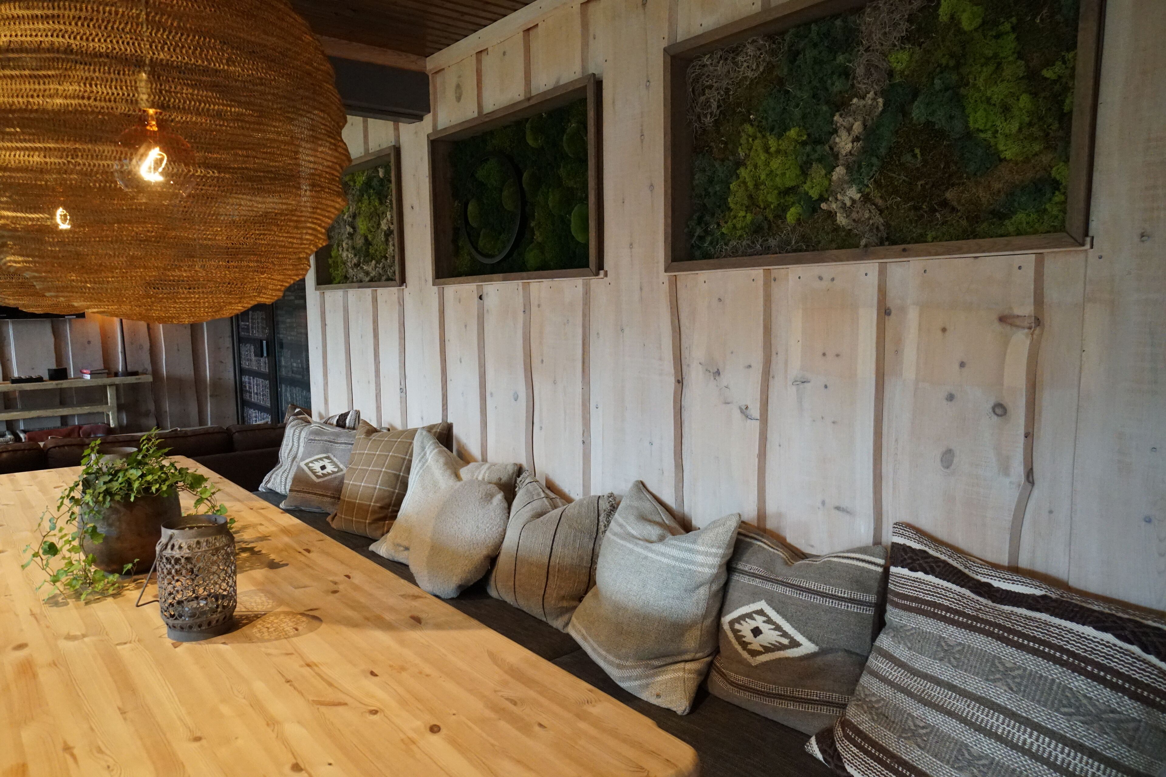 Un comedor de madera con una mesa larga, asientos acolchados y una lámpara colgante.