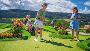 Golfers enjoy a round on the well-manicured course amidst rolling hills and beautiful flower beds.