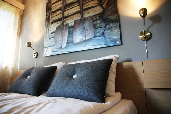 A neatly made bed with two pillows, a wall-mounted painting, and a wall-mounted light fixture. - Lillehammer Turistsenter Budget Hotel (Lillehammer)