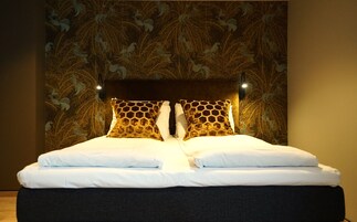 Una cama con sábanas blancas y dos almohadones decorativos con diseño de panal.
