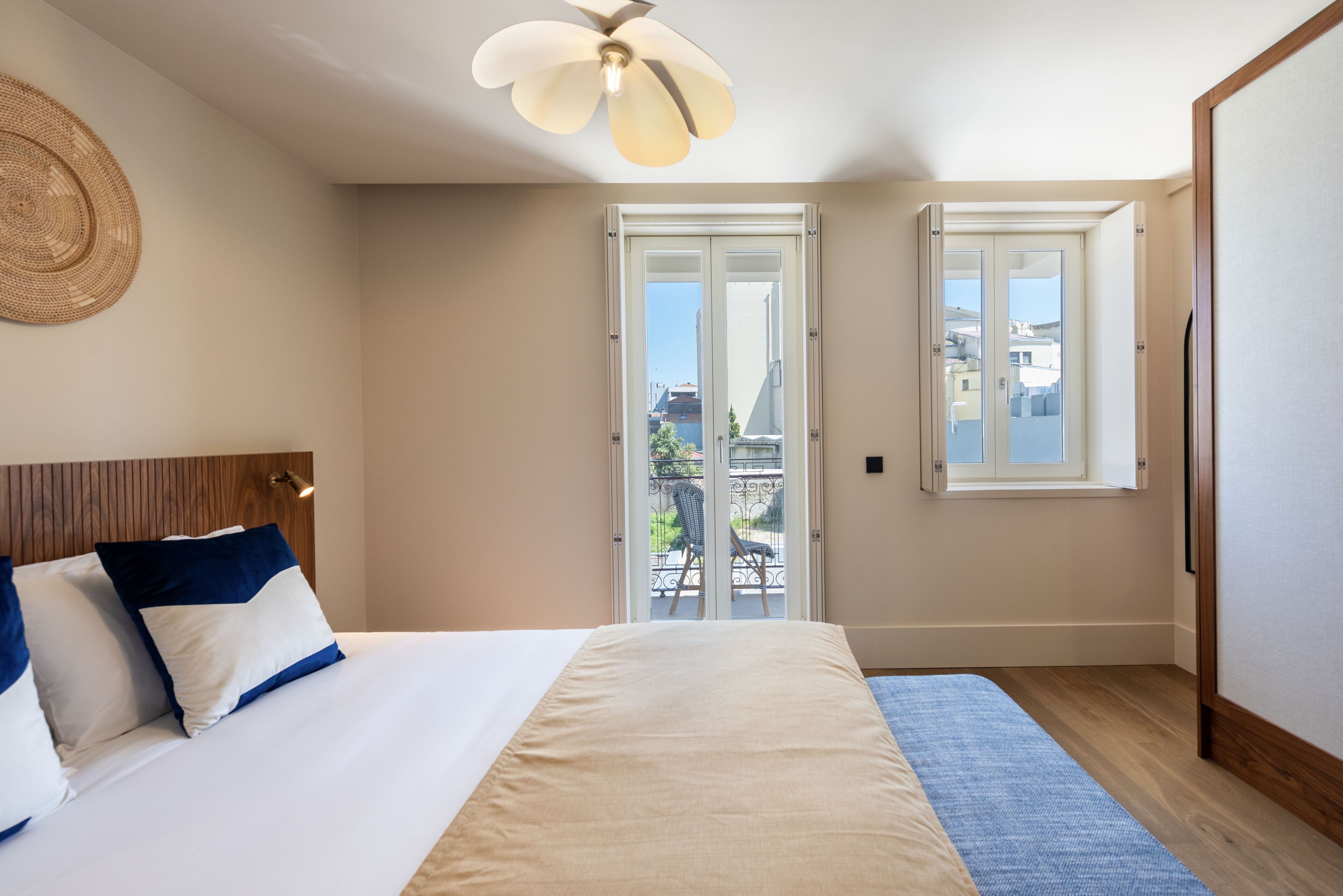 Una camera da letto con un letto, una ventola a soffitto, una porta finestra e vista sulla città.