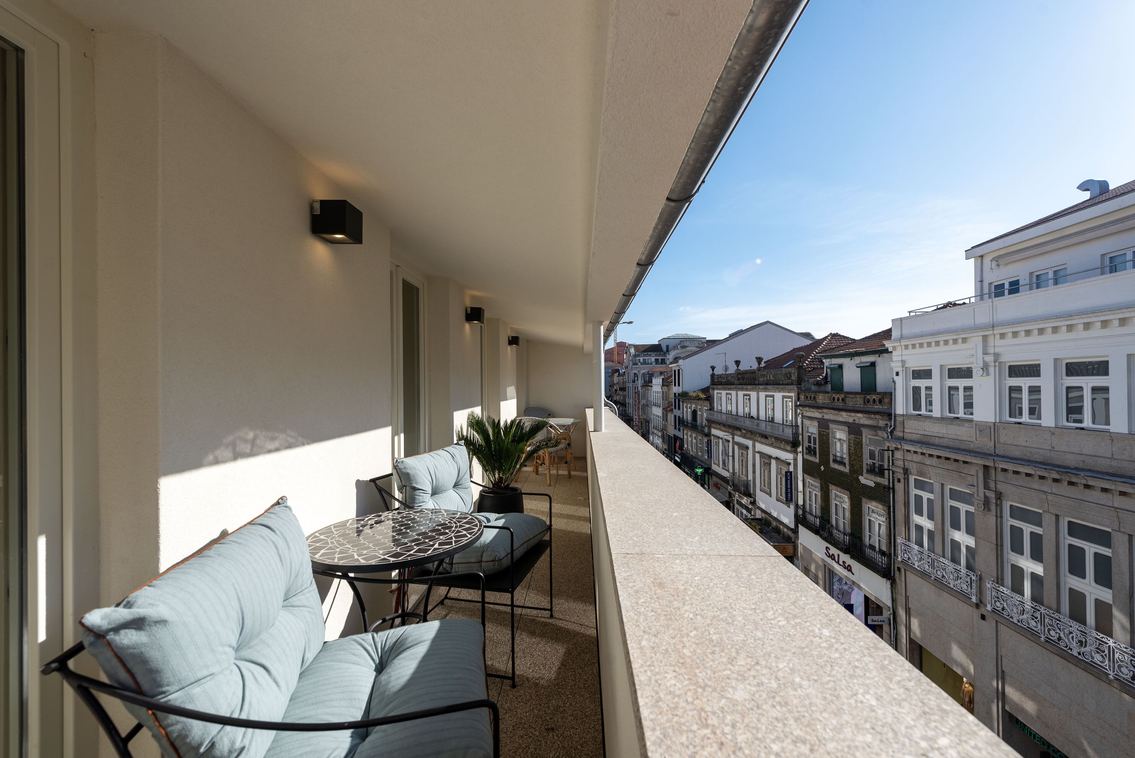 A balcony with a sofa, a small table, and a potted plant.