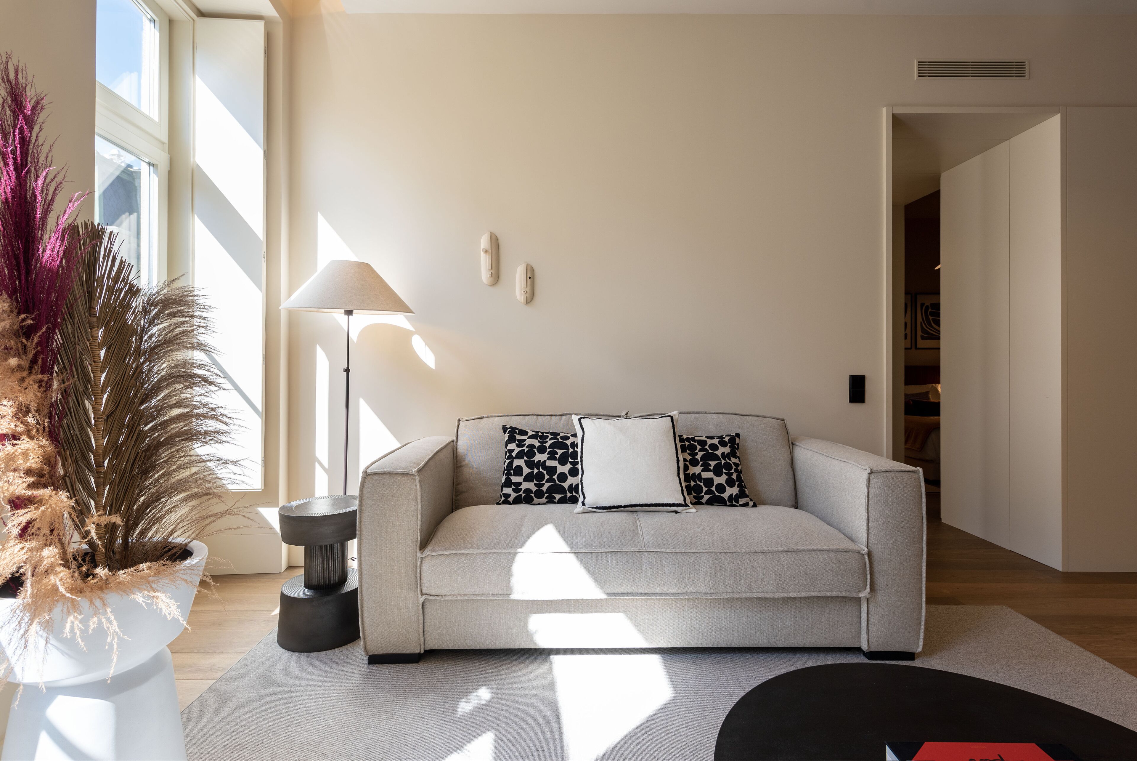 A modern living room with a sofa, a floor lamp, and a potted plant.