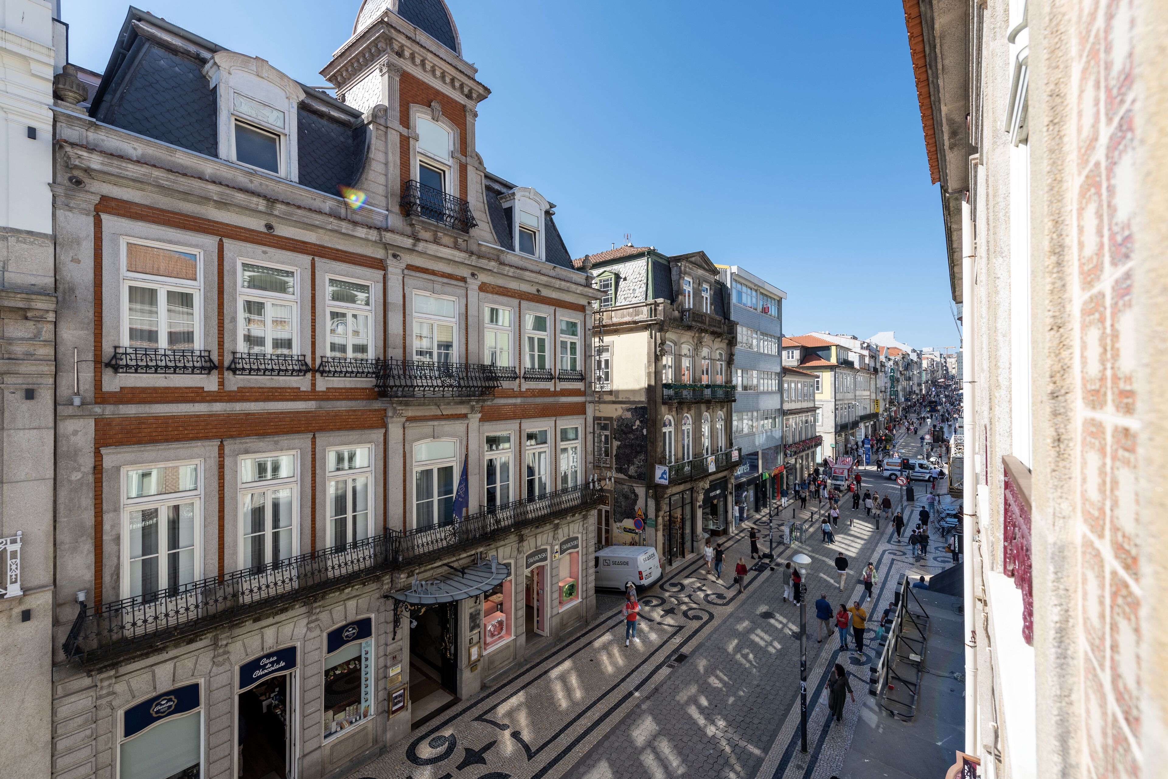A street view of a historic European town with traditional architecture, cobblestone streets, and a clear blue sky.