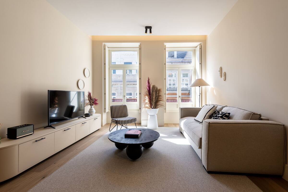Un salon moderne avec un téléviseur à écran plat, un canapé, une table basse et un fauteuil.