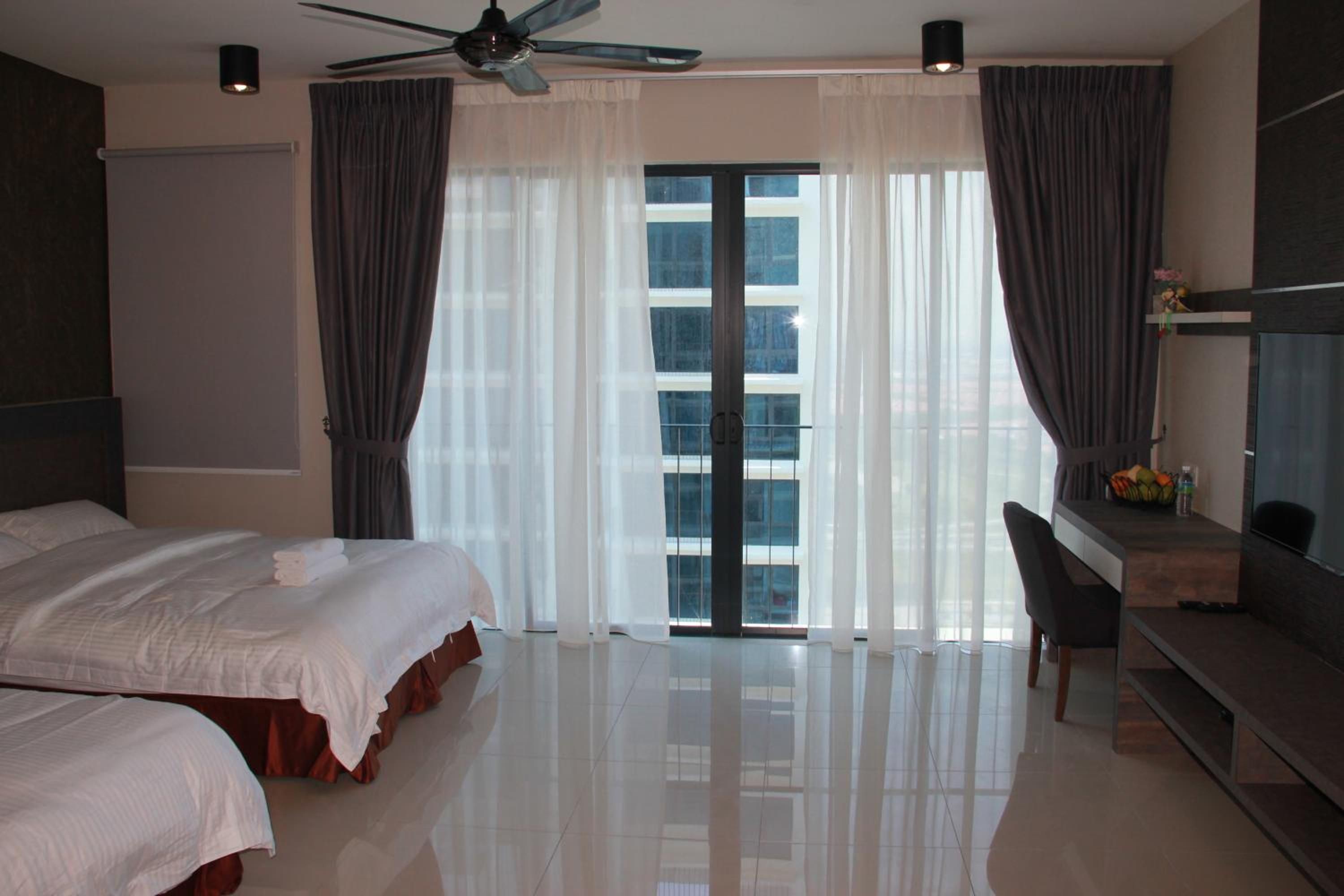 A hotel room with a bed, a desk, and a view of the city through large windows.
