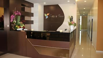 A reception desk with a modern design, a logo, and a flower arrangement.