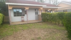 Una casa de dos pisos con techo de tejas, un pequeño porche y un césped bien cuidado.