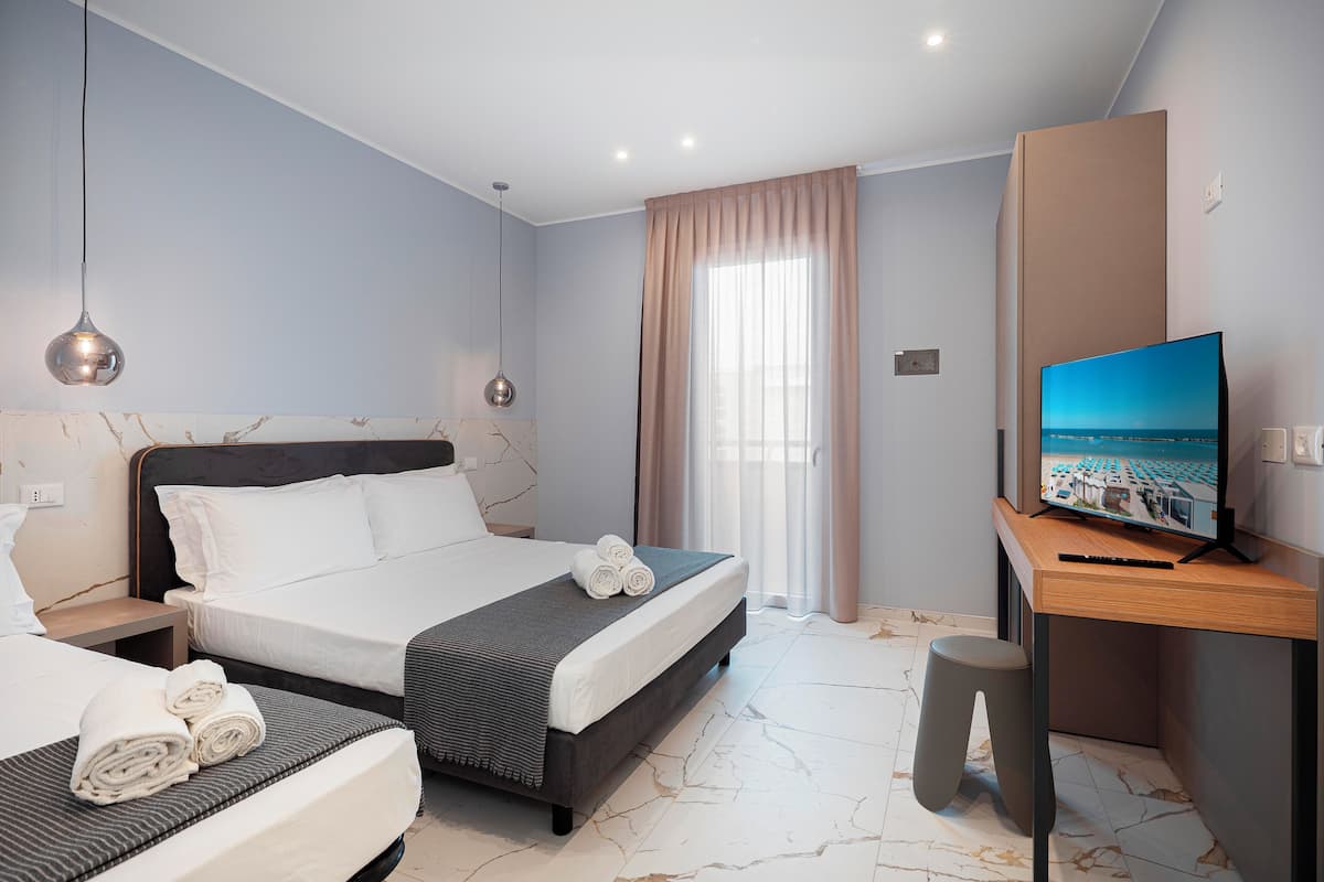 Una habitación de hotel moderna con una cama grande, un escritorio con televisión de pantalla plana y un taburete pequeño.