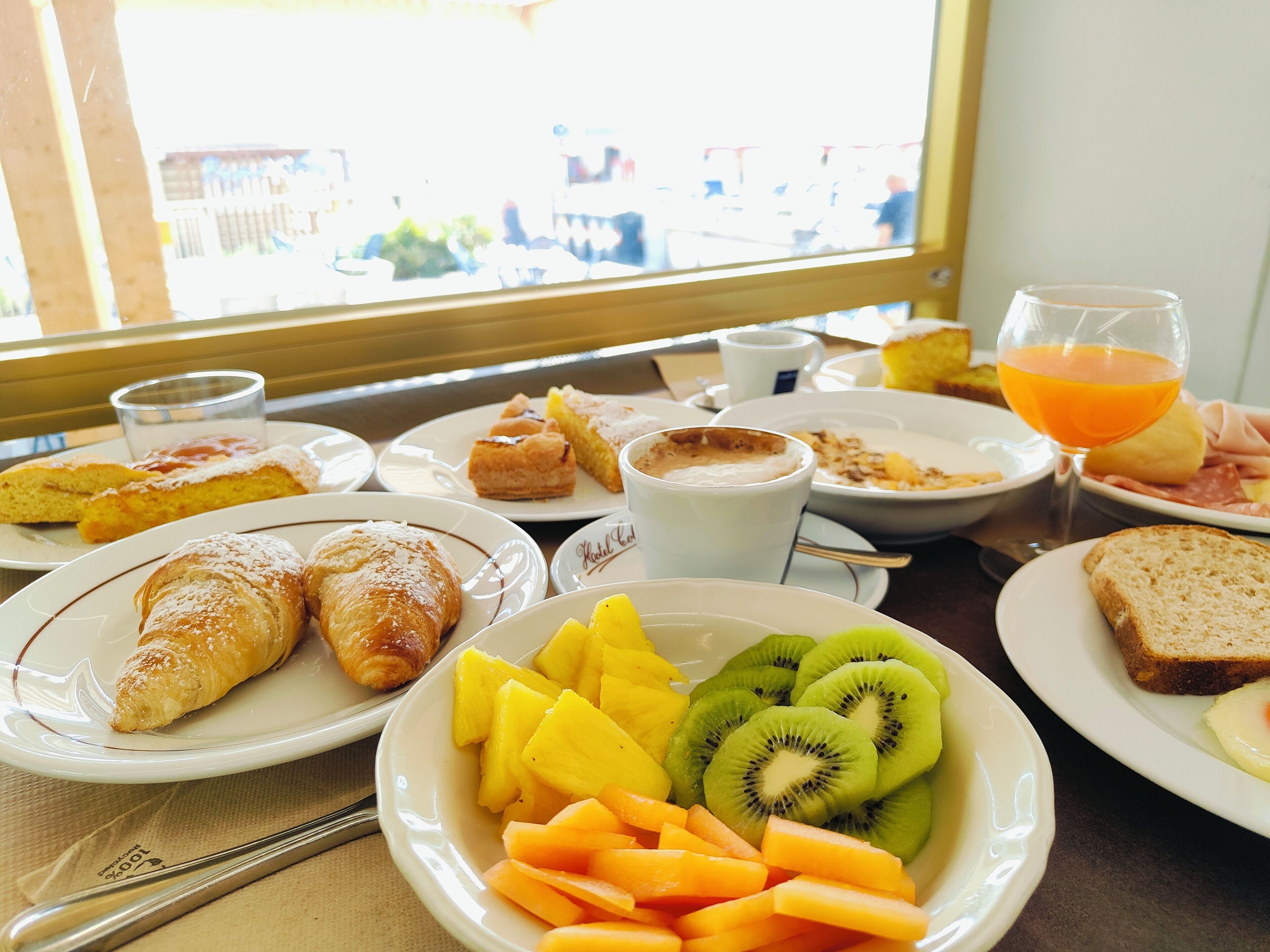 Una mesa de desayuno con cruasanes, fruta, café y jugo.